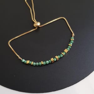 Puede incluir: Pulsera ajustable dorada con peque&ntilde;as cuentas verdes redondas y cuentas rectangulares doradas. La pulsera tiene una cadena delicada y un cierre deslizante. Adecuada para mu&ntilde;ecas de hasta 20 cm.