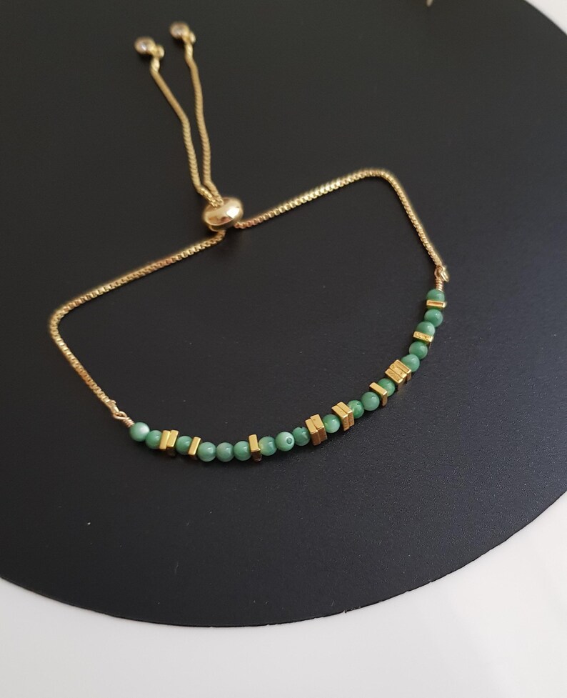 Puede incluir: Pulsera ajustable dorada con peque&ntilde;as cuentas verdes redondas y cuentas rectangulares doradas. La pulsera tiene una cadena delicada y un cierre deslizante. Adecuada para mu&ntilde;ecas de hasta 20 cm.