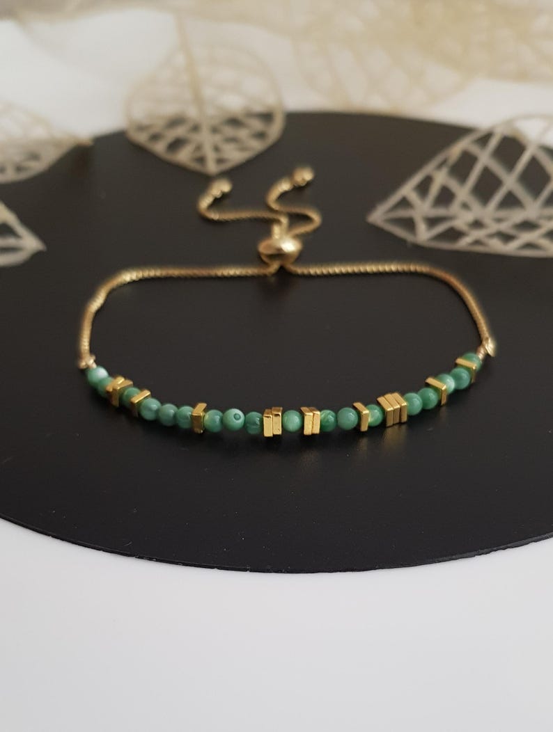 Puede incluir: Pulsera ajustable dorada con cuentas verdes y detalles cuadrados dorados. La pulsera tiene una cadena fina y un cierre deslizante. El dise&ntilde;o es sencillo y elegante, adecuado para el uso diario o ocasiones especiales. La longitud es ajustable.
