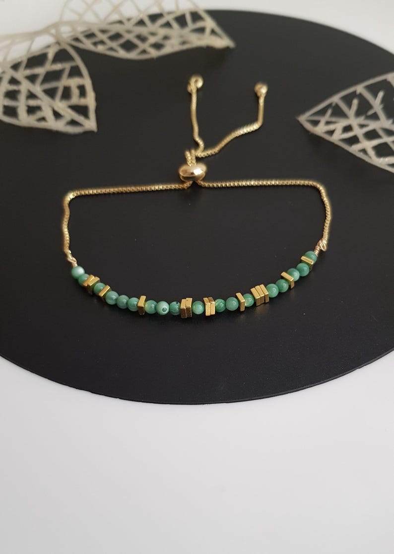 Puede incluir: Pulsera dorada con peque&ntilde;as cuentas verdes redondas y cuentas rectangulares doradas. La pulsera tiene una cadena ajustable y un peque&ntilde;o cierre redondo dorado.