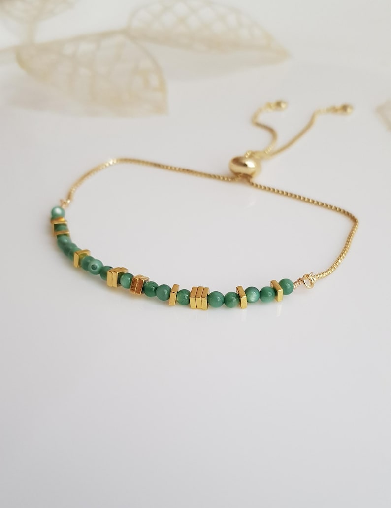 Puede incluir: Pulsera ajustable dorada con peque&ntilde;as cuentas verdes redondas y cuentas cuadradas doradas. La pulsera tiene una cadena delicada y un cierre deslizante. Adecuada para mu&ntilde;ecas de hasta 20 cm.