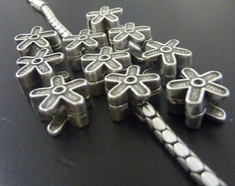 May include: Close-up of a silver-toned rosary with flower-shaped beads. The beads are arranged in a cluster, with a detailed chain visible. The background is a dark, solid color.