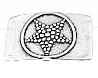 May include: A rectangular, silver-coloured belt buckle with a raised, circular design. Inside the circle is a five-pointed star, made of small, raised dots. The buckle has a slightly distressed, vintage appearance.