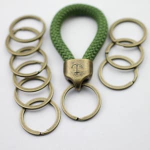 Può includere: Un portachiavi in corda verde con un'emblema di ancora color bronzo e portachiavi in bronzo. Il portachiavi ha un design ad anello, adatto per chiavi o per attaccare a borse. I portachiavi sono di varie dimensioni.