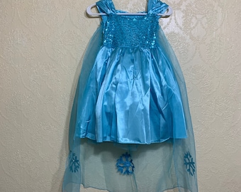 May include: A light blue dress with a sequined bodice and a tulle overlay. The dress has snowflake embellishments on the tulle.