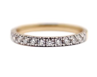 May include: A gold and silver ring with a band of small, round, clear gemstones. The ring is set against a white background, highlighting the sparkle of the gemstones. The ring is a piece of jewelry.