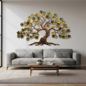 Könnte beinhalten: Ein großes Metall-Wandkunstwerk, das einen Baum mit Blättern in Grün- und Goldtönen und einem braunen Stamm darstellt. Mehrere kleine Vögel sitzen auf den Ästen. Das Kunstwerk ist an einer weißen Wand über einem grauen Sofa angebracht.
