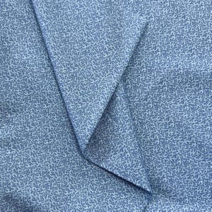 May include: A close-up of folded light blue fabric with a small, all-over dot pattern in a darker blue. The fabric is arranged to create a triangular shape, highlighting the pattern and texture of the material.