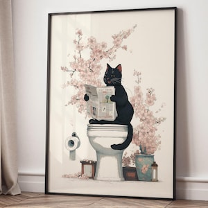 Può includere: Stampa artistica incorniciata con un gatto nero seduto su un water, che legge un giornale. L'opera d'arte include rami fioriti rosa, un rotolo di carta igienica e un piccolo vaso con fiori. La stampa è in una cornice nera.