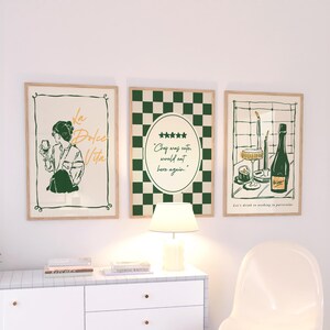 May include: Three framed art prints with a vintage aesthetic. The prints feature illustrations in green and beige tones, including a woman with a wine glass, a checkered pattern, and a wine bottle with glasses. The text includes "La Dolce Vita" and "Chef was cuter, would eat here again."