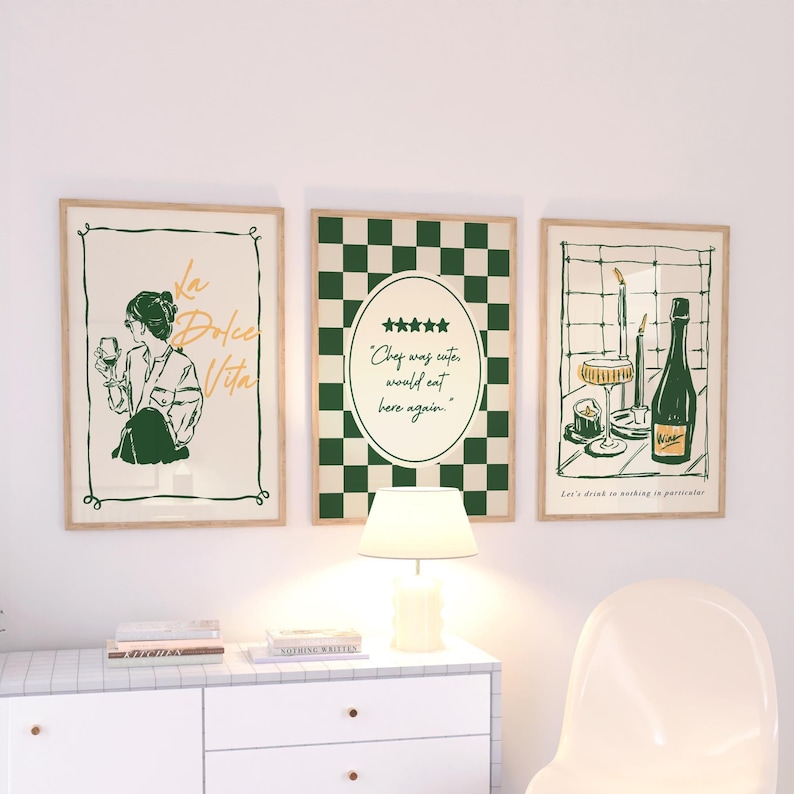 May include: Three framed art prints with a vintage aesthetic. The prints feature illustrations in green and beige tones, including a woman with a wine glass, a checkered pattern, and a wine bottle with glasses. The text includes "La Dolce Vita" and "Chef was cuter, would eat here again."