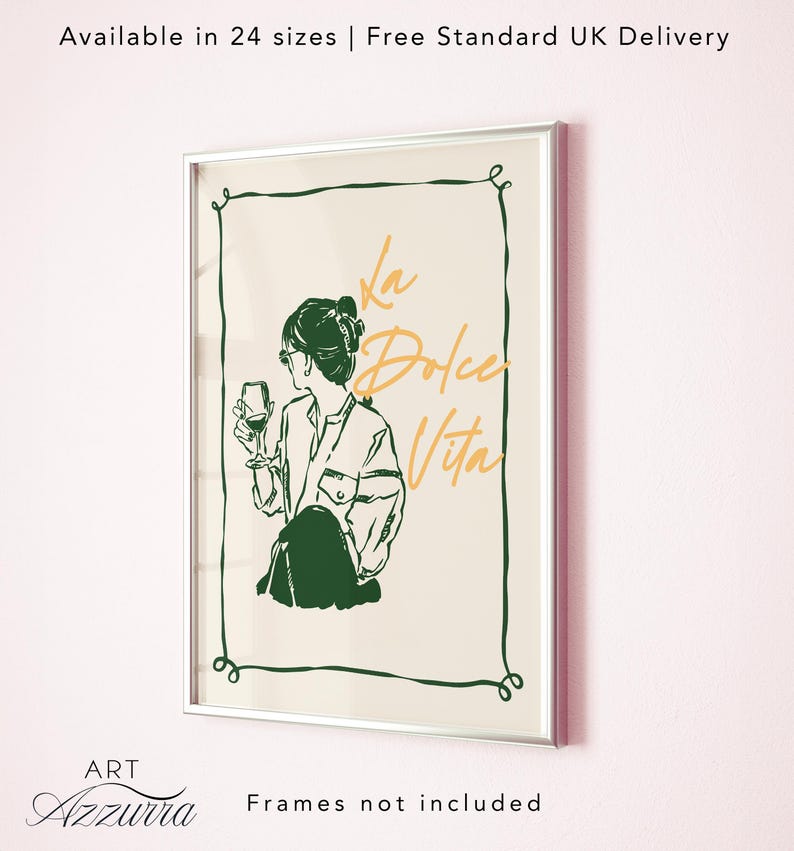 May include: A framed art print with a silver border. The artwork features a line drawing of a person holding a wine glass, with the words "La Dolce Vita" in gold script. The print has a cream background and a green decorative border.