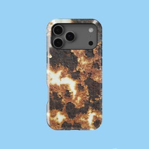 May include: A phone case with a textured, rust-like design in shades of brown, orange, and white. The case has a dark gray camera module with three lenses and a flash. The case is set against a light blue background.