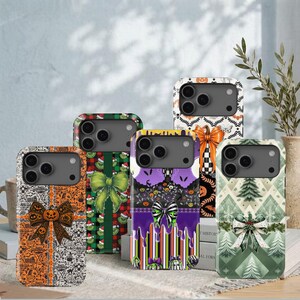 May include: Five smartphone cases featuring festive designs. One has orange pumpkins and bows, one has green plaid with a bow, one has purple drips and a striped bow, one has a black and white pattern with an orange bow, and one has green trees.