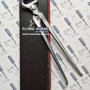 May include: A pair of farrier's nippers, made of steel, resting on a black leather case with red stitching. The nippers are designed for trimming horse hooves. The case has the text "FLYING HORSE ENTERPRISES" and website address.