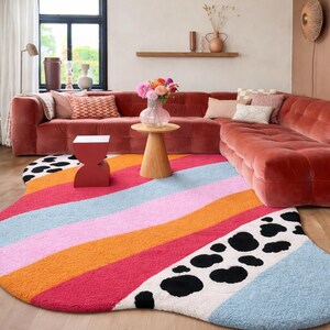 Irregular blob shaped pastel stripe rug with black and white cow print detail in aesthetic living room