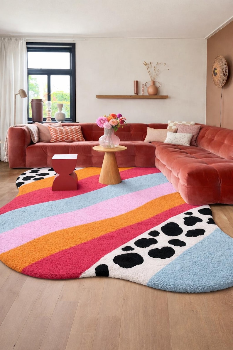 Irregular blob shaped pastel stripe rug with black and white cow print detail in aesthetic living room