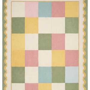 Soft plush pastel checkerboard nursery rug with scalloped border in blush pink, sage green, cream, butter yellow, and baby blue tones. This tufted kids room carpet is styled in a dreamy rainbow-themed nursery and adds cozy cottagecore charm to playrooms, baby rooms, and modern children’s spaces. Perfect for pastel aesthetic decor, soft nursery interiors, Montessori playrooms, and colorful bedroom styling for toddlers and babies