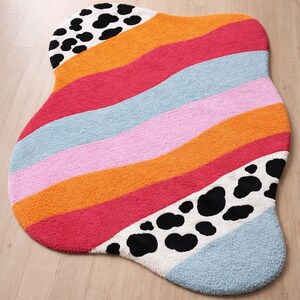 Irregular blob shaped pastel stripe rug with black and white cow print detail