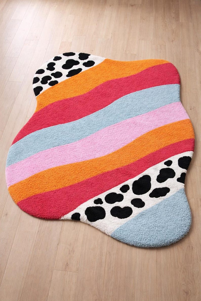 Irregular blob shaped pastel stripe rug with black and white cow print detail
