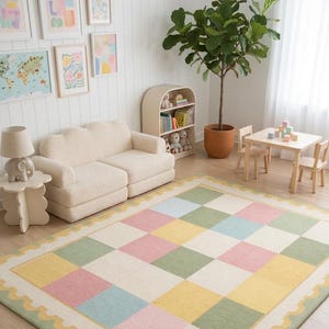 Soft plush pastel checkerboard nursery rug with scalloped border in blush pink, sage green, cream, butter yellow, and baby blue tones. This tufted kids room carpet is styled in a dreamy rainbow-themed nursery and adds cozy cottagecore charm to playrooms, baby rooms, and modern children’s spaces. Perfect for pastel aesthetic decor, soft nursery interiors, Montessori playrooms, and colorful bedroom styling for toddlers and babies