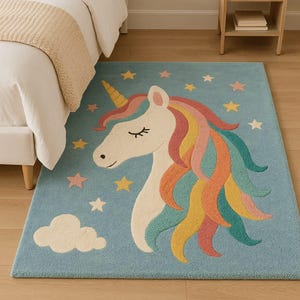 May include: A rectangular area rug with a light blue background featuring a white unicorn head with a yellow horn and a multi-colored mane in shades of pink, orange, yellow, and teal. The design includes scattered stars and a white cloud.