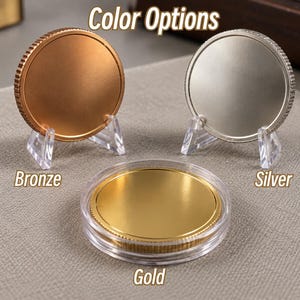 May include: Three circular metal coins labeled Color Options. One bronze coin and one silver coin are displayed upright on clear plastic stands. One gold coin is encased in a clear circular protective plastic capsule in the foreground.
