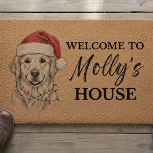 May include: A rectangular tan coir doormat featuring a black printed inscription that reads WELCOME TO Molly's HOUSE. To the left, a detailed illustration of a golden retriever wearing a red Santa hat and a string of colorful Christmas lights.