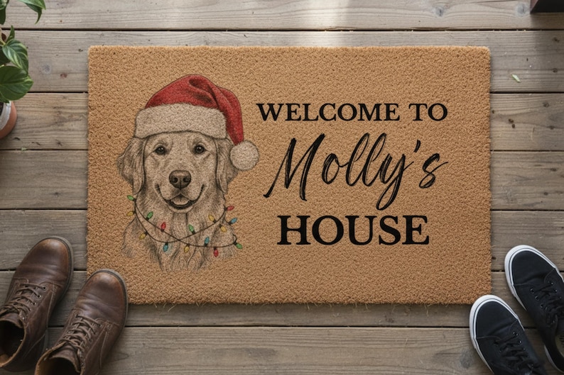 May include: A rectangular tan coir doormat featuring a black printed inscription that reads WELCOME TO Molly's HOUSE. To the left, a detailed illustration of a golden retriever wearing a red Santa hat and a string of colorful Christmas lights.