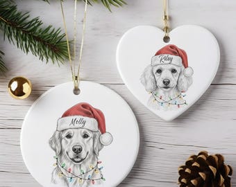 May include: Two white ceramic Christmas ornaments. One is round, the other heart-shaped. Both feature a dog wearing a Santa hat and string lights. The round ornament says "Molly" and the heart-shaped ornament says "Riley".