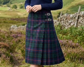 May include: A navy blue long-sleeved ribbed sweater paired with a knee-length pleated kilt featuring a green, blue, and red plaid pattern. The kilt includes two adjustable side buckle straps. Also includes navy blue knee-high socks and brown boots.