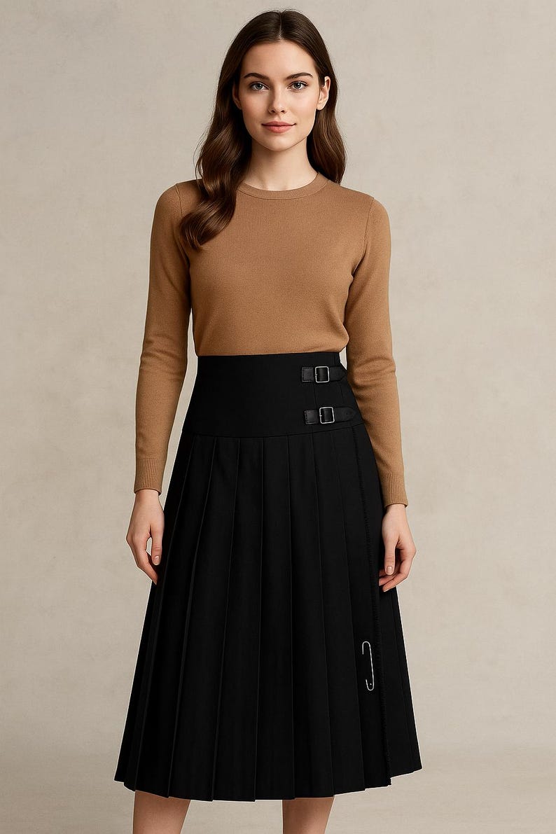 May include: A woman wearing a brown long-sleeve sweater and a black pleated skirt. The skirt has a high waist with two buckle details and a safety pin. The outfit is a classic and elegant style.