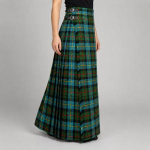 May include: A floor-length pleated kilt skirt featuring a traditional tartan pattern in shades of green, blue, black, and yellow with thin red lines. The garment includes a wrap-around design with two adjustable black leather straps and metal buckles.