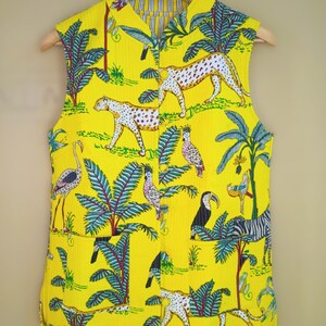 May include: Yellow sleeveless vest with a vibrant jungle print featuring leopards, birds, and palm trees. The vest has a button-up front and a stand-up collar. The lining is striped.