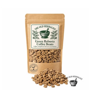 May include: A brown paper pouch containing green Robusta coffee beans with a clear window. The label reads THE OLD HERBALIST, Green Robusta Coffee Beans, Coffea canephora Pierre ex A.Froehner, and 100% PURELY NATURAL. A pile of beans sits in front.