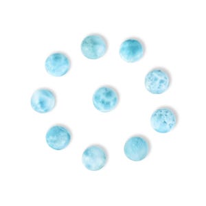 May include: A collection of ten round, light blue larimar gemstones arranged in a circle on a white background. The stones have a marbled appearance with varying shades of blue and white.