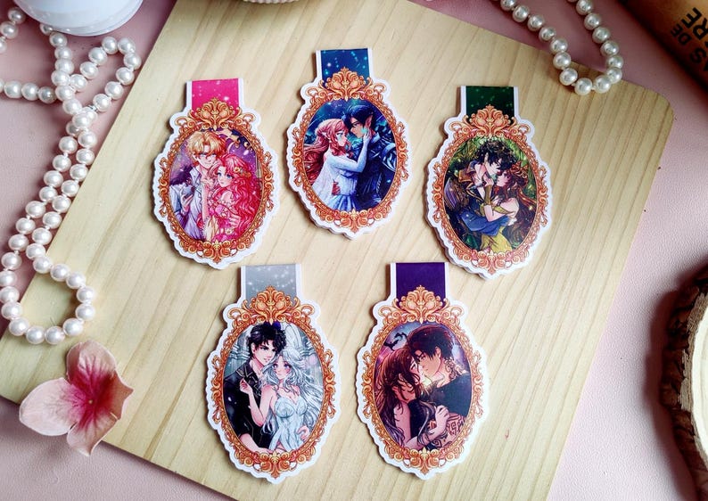 Puede incluir: Cinco marcap&aacute;ginas decorativos con ilustraciones rom&aacute;nticas de estilo anime. Cada marcap&aacute;ginas presenta una pareja diferente en un marco ovalado decorativo con un borde dorado. Los marcap&aacute;ginas tienen pesta&ntilde;as de diferentes colores.
