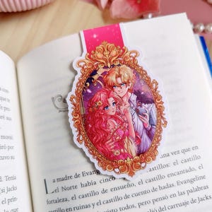 Puede incluir: Marcap&aacute;ginas decorativo con una ilustraci&oacute;n rom&aacute;ntica de una pareja en un marco dorado adornado. El marcap&aacute;ginas est&aacute; en un libro abierto. La parte superior del marcap&aacute;ginas es rosa. El libro tiene texto.