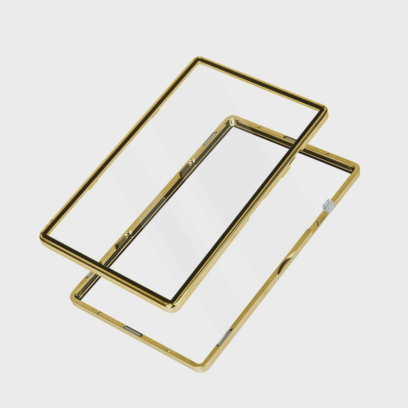May include: Two clear phone cases with gold-colored frames. The cases are rectangular with rounded corners and a black border around the clear screen area. One case is slightly offset from the other.