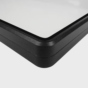 Puede incluir: Primer plano de un marco rectangular negro con interior blanco. El marco tiene una superficie texturizada y esquinas redondeadas. La imagen est&aacute; sobre un fondo liso y claro.