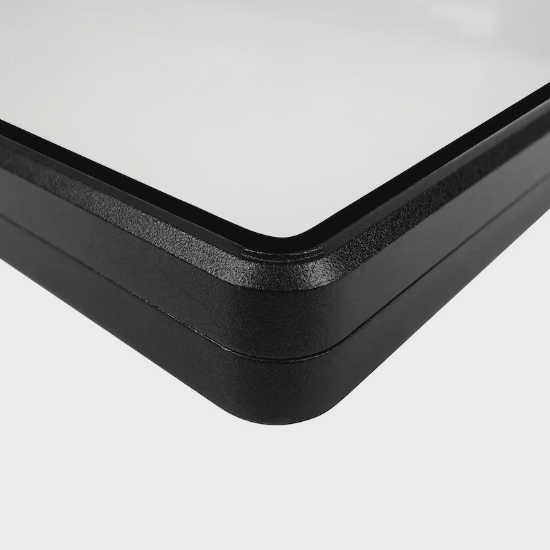 Puede incluir: Primer plano de un marco rectangular negro con interior blanco. El marco tiene una superficie texturizada y esquinas redondeadas. La imagen est&aacute; sobre un fondo liso y claro.