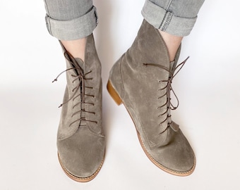 May include: A pair of gray suede lace-up ankle boots with brown laces and a brown sole.