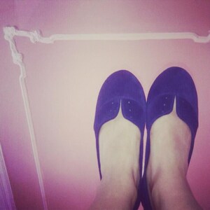 May include: A pair of purple suede ballet flats with a pointed toe.