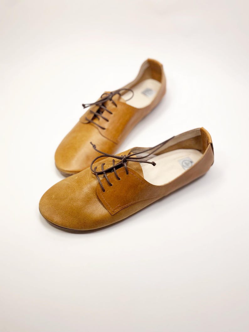 May include: Two pairs of brown leather lace-up shoes with a pointed toe.