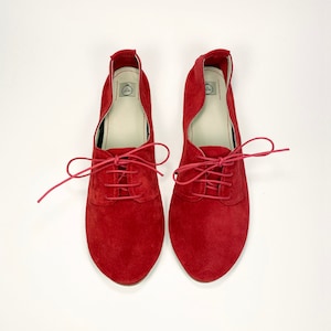 May include: A pair of red suede lace-up shoes with a pointed toe.