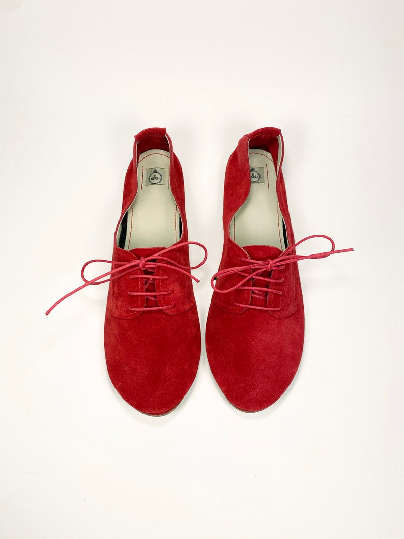 May include: A pair of red suede lace-up shoes with a pointed toe.