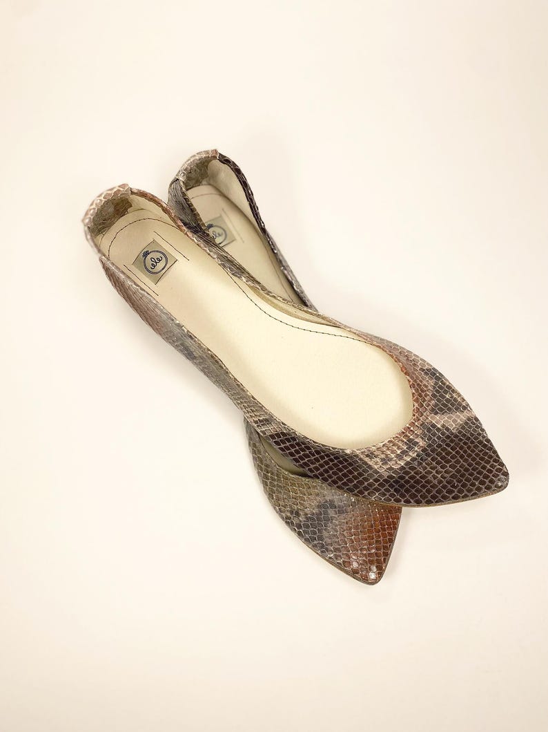 Peut inclure: Deux ballerines &agrave; bout pointu avec un motif peau de serpent dans les tons marron, gris et beige. Les chaussures ont un petit talon et un int&eacute;rieur lisse blanc cass&eacute;. Ces chaussures sont con&ccedil;ues pour le confort et le style.