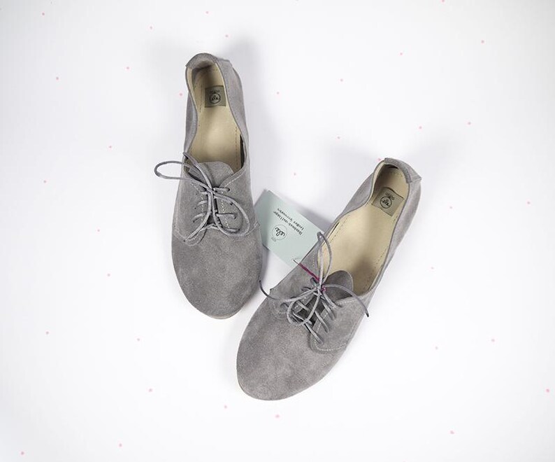 May include: A pair of gray suede lace-up shoes with a rounded toe.