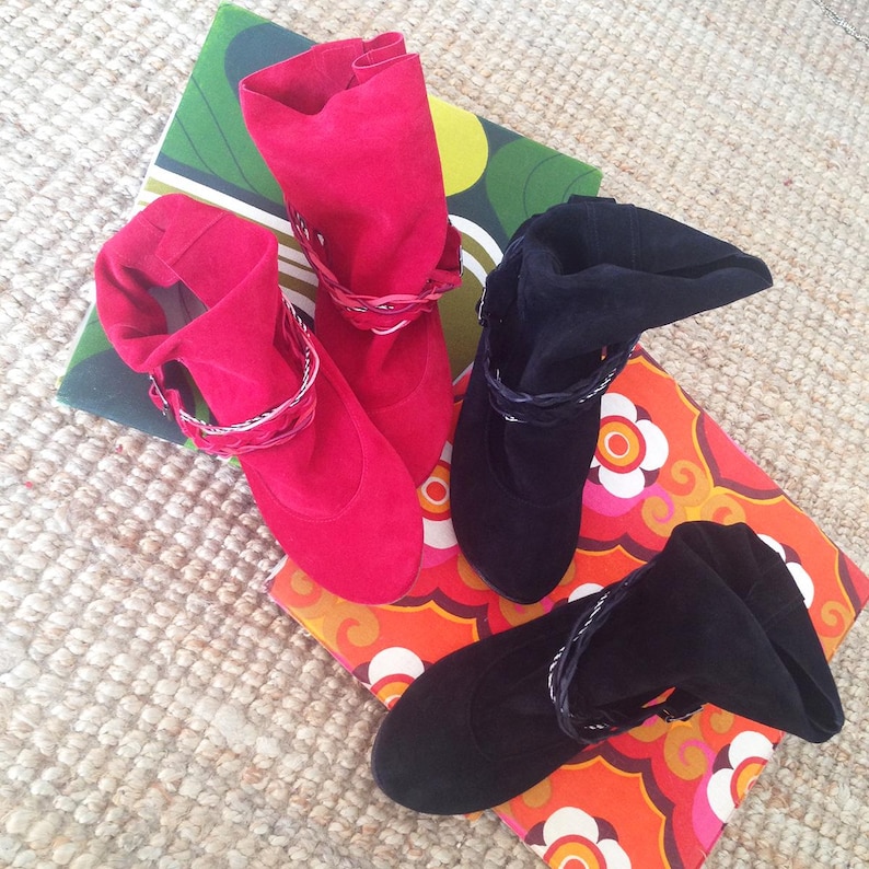May include: Two pairs of ankle boots with decorative braided straps. One pair is red suede and the other is black suede.