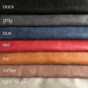 May include: A stack of seven different colored leather swatches, from top to bottom: black, gray, blue, red, tan, toffee, and light taupe.